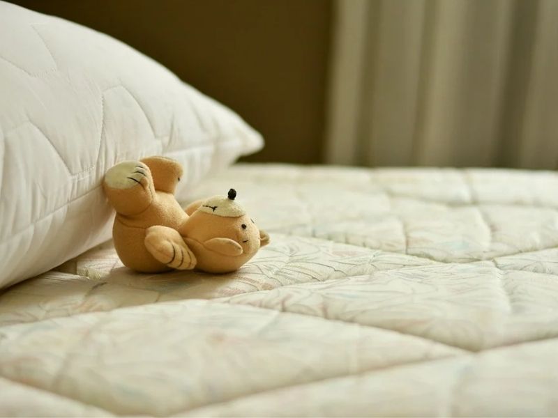 Matelas et oreiller dénudés avec un petit ours en peluche posé dessus